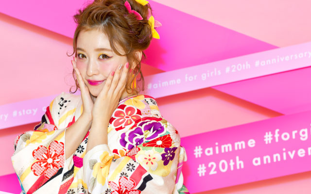 ビビッドなピンク色の背景で20歳の女の子がサングラスを持っている写真